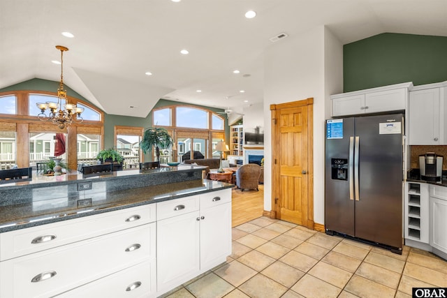 kitchen with lofted ceiling, stainless steel fridge, visible vents, and white cabinetry