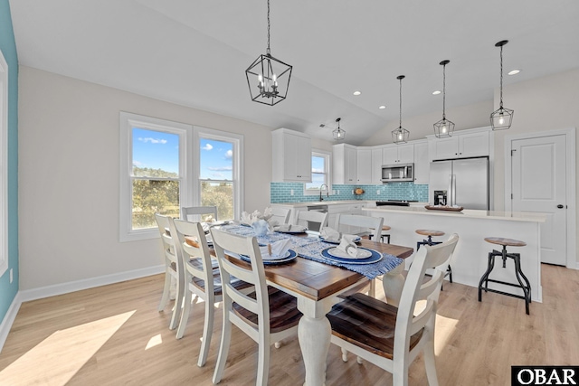 dining area with lofted ceiling, light wood-style flooring, recessed lighting, baseboards, and a chandelier