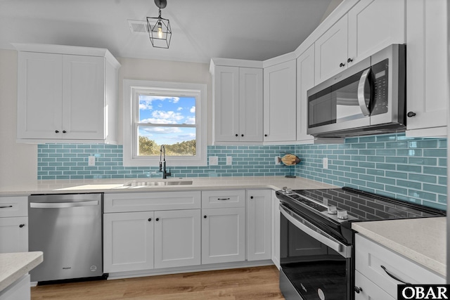 kitchen with a sink, white cabinetry, appliances with stainless steel finishes, and light countertops