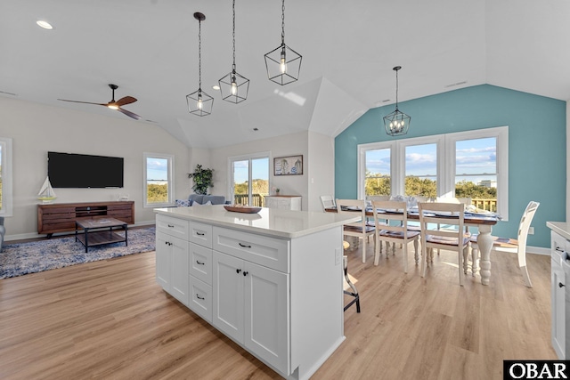 kitchen featuring light wood-style flooring, hanging light fixtures, vaulted ceiling, white cabinets, and ceiling fan with notable chandelier