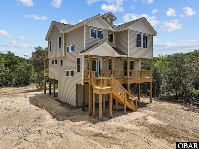 beach home featuring dirt driveway, stairway, board and batten siding, and roof with shingles