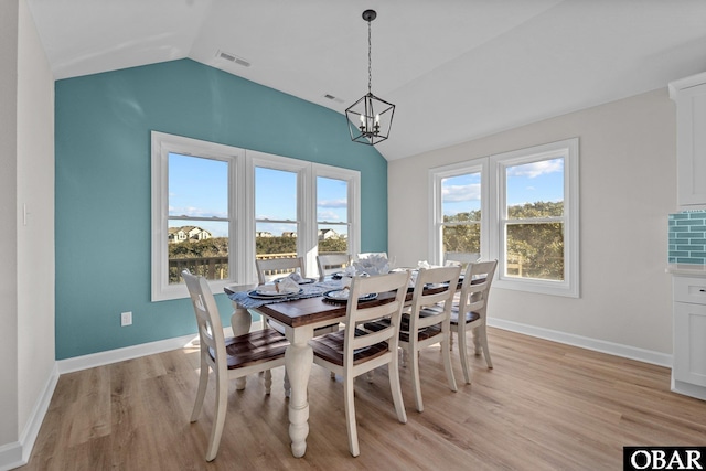 dining space with light wood finished floors, visible vents, baseboards, lofted ceiling, and a notable chandelier