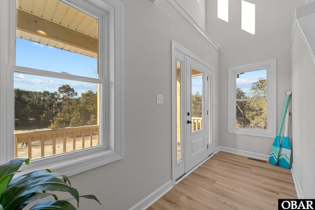 foyer entrance with light wood-style flooring, visible vents, and baseboards