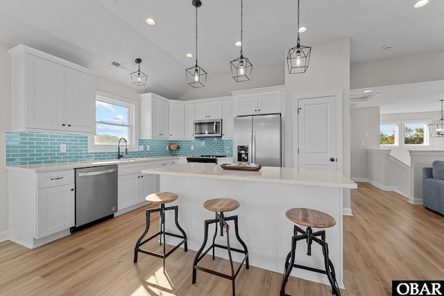 kitchen featuring a breakfast bar, light countertops, white cabinets, and appliances with stainless steel finishes