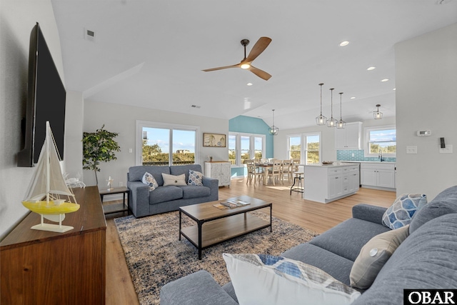 living room featuring light wood finished floors, visible vents, ceiling fan, vaulted ceiling, and recessed lighting