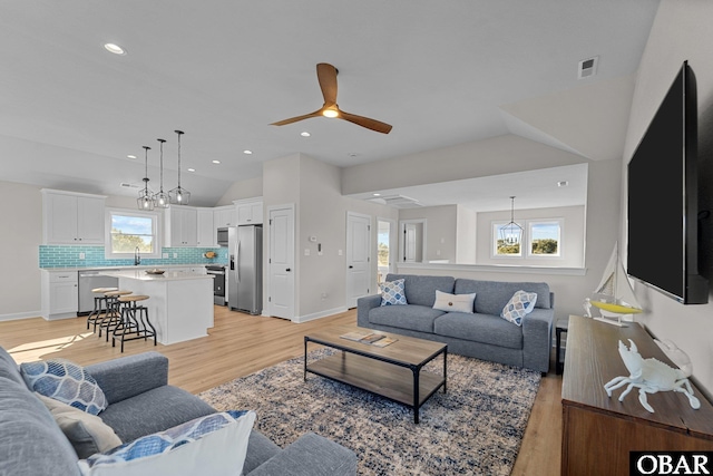 living room featuring visible vents, lofted ceiling, recessed lighting, ceiling fan, and light wood-type flooring