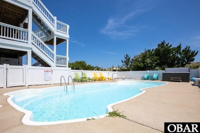 community pool featuring a patio, stairway, and fence