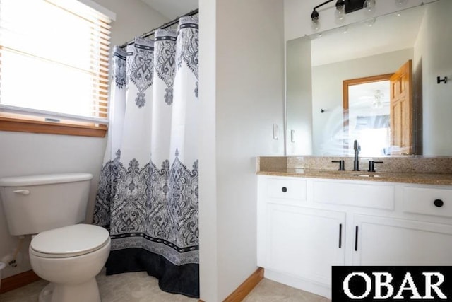 bathroom featuring toilet, plenty of natural light, vanity, and baseboards