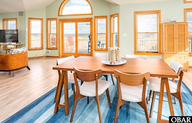 dining room featuring lofted ceiling, light wood-style floors, and baseboards