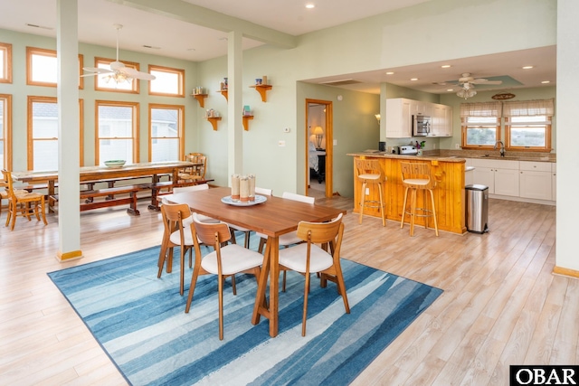 dining area featuring light wood-style floors, a ceiling fan, and a wealth of natural light