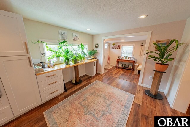 office area featuring plenty of natural light, a textured ceiling, recessed lighting, wood finished floors, and built in desk