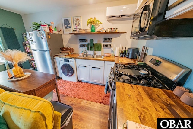 kitchen featuring butcher block countertops, washer / clothes dryer, stainless steel appliances, and a sink