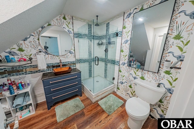 full bathroom featuring wood finished floors, a stall shower, toilet, vanity, and wallpapered walls