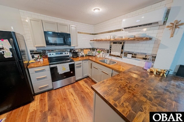 kitchen featuring black appliances, butcher block countertops, tasteful backsplash, and a textured ceiling