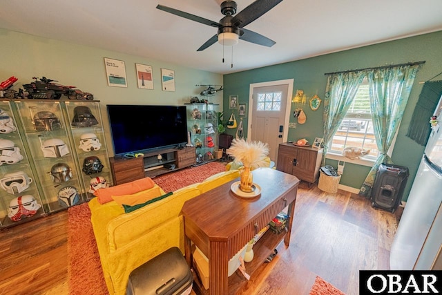 living area with wood finished floors, a ceiling fan, and baseboards