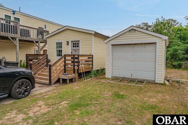 view of front of house featuring a deck, a garage, a front lawn, and an outbuilding