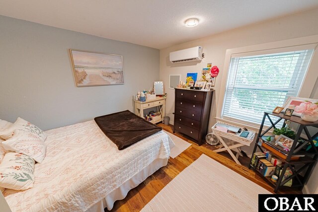 bedroom with a wall unit AC and wood finished floors