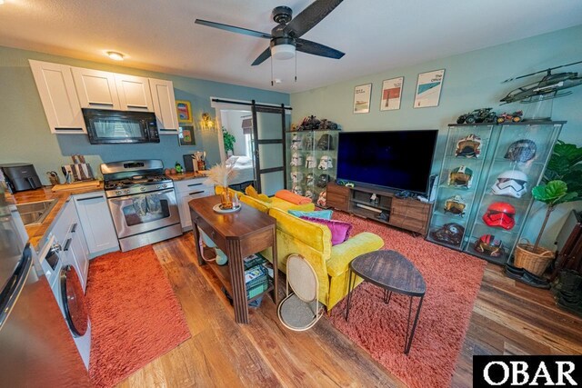 living area featuring a barn door, light wood finished floors, and a ceiling fan