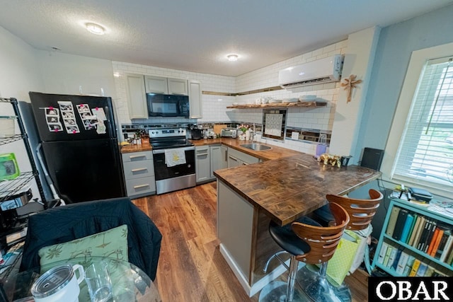 kitchen featuring black appliances, a wall unit AC, butcher block counters, a sink, and backsplash