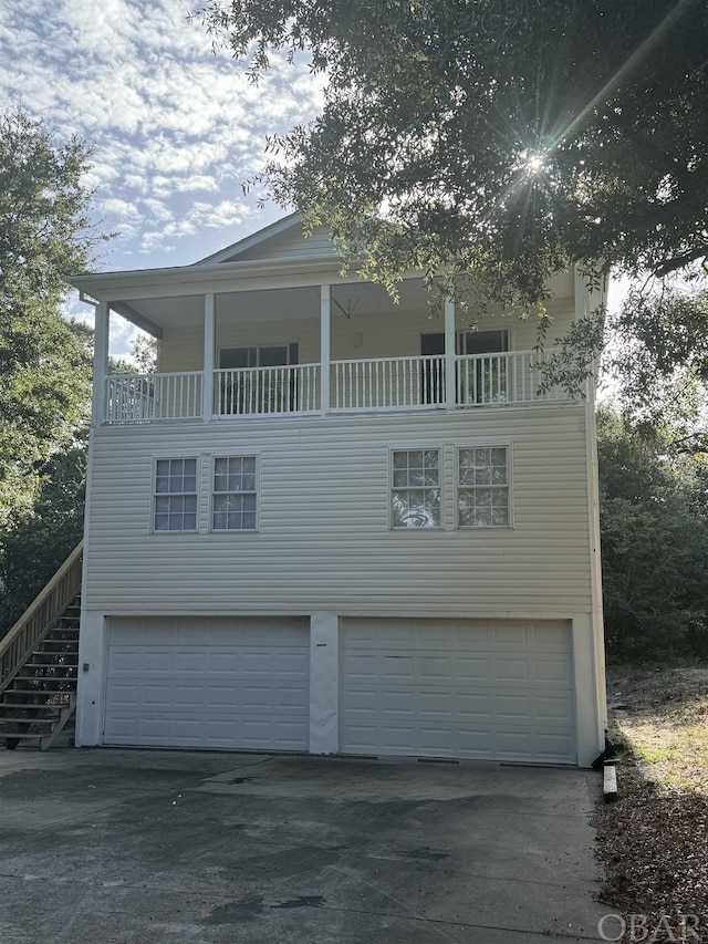 view of front of home featuring a balcony, an attached garage, and stairs