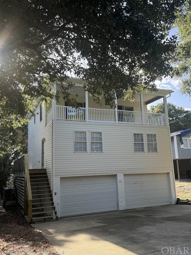 view of front of property featuring stairs, concrete driveway, a balcony, and a garage