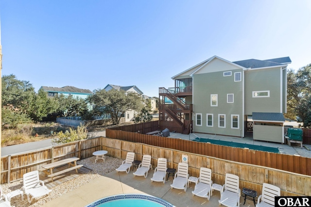 rear view of house featuring stairs, a patio area, a fenced backyard, and a fenced in pool