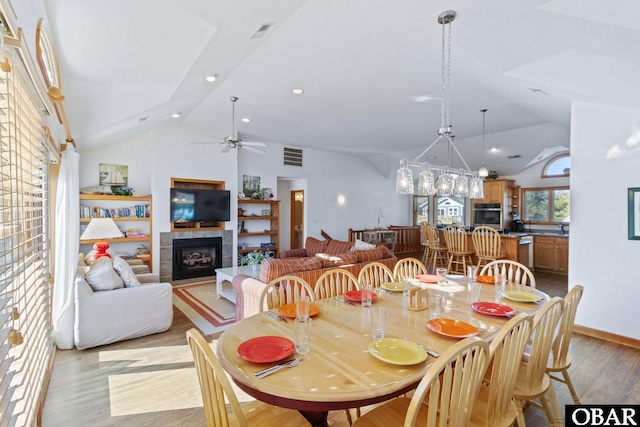 dining room with a ceiling fan, visible vents, light wood-style flooring, recessed lighting, and a tile fireplace