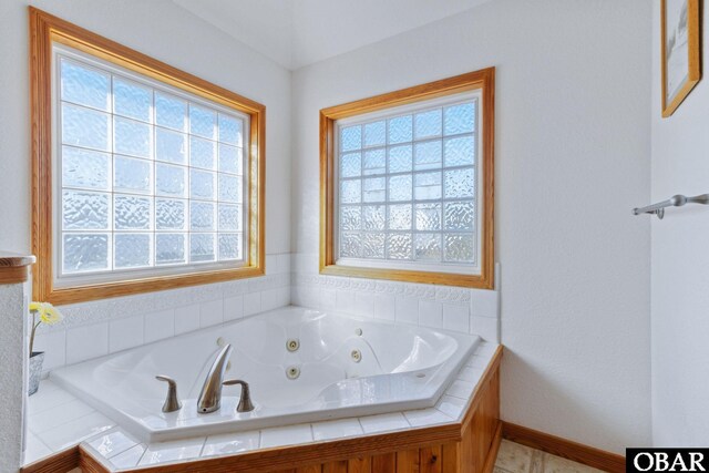 full bath featuring a whirlpool tub and baseboards