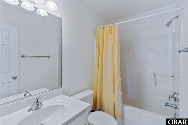 bathroom featuring toilet, vanity, a textured wall, and shower / bath combo