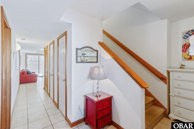 hall featuring light tile patterned floors, stairway, and baseboards