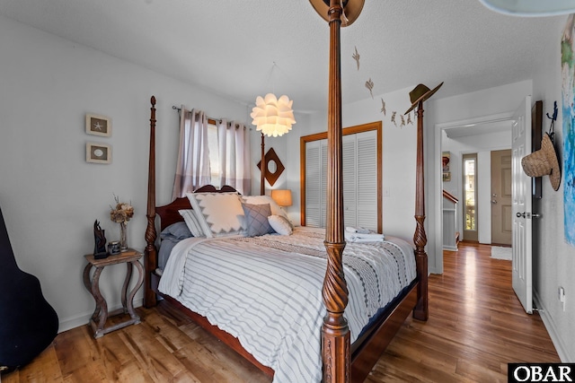 bedroom featuring baseboards, multiple windows, a closet, and wood finished floors