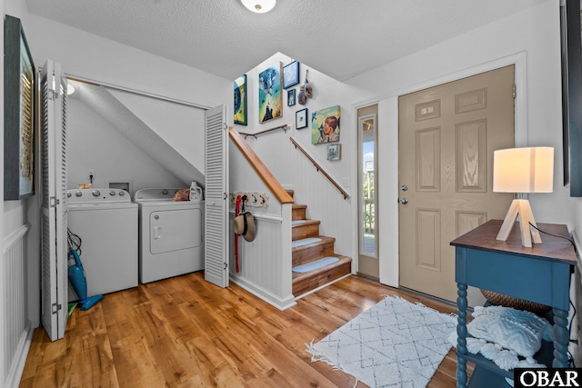 foyer with wood finished floors, a textured ceiling, stairs, and washing machine and dryer