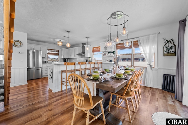 dining room with wood finished floors, a wainscoted wall, and a wealth of natural light