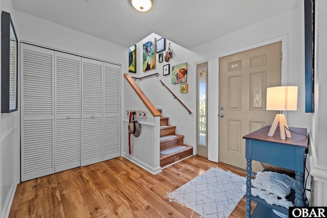foyer with a textured ceiling, light wood-style flooring, and stairway