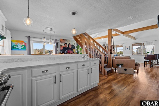 kitchen with a textured ceiling, pendant lighting, gas stove, white cabinets, and dark wood-type flooring