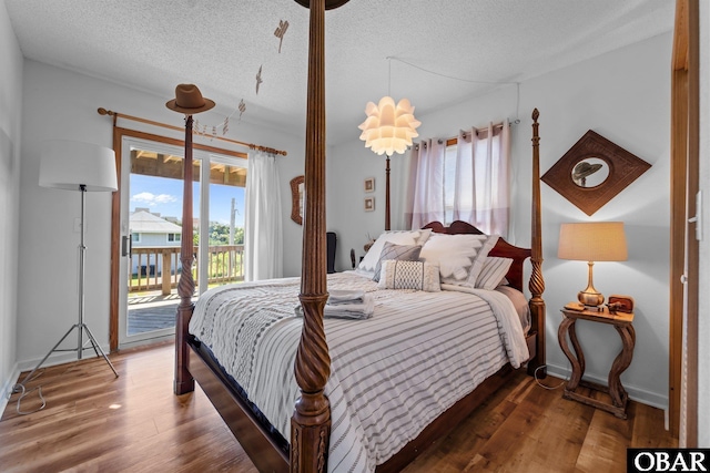 bedroom with access to outside, a textured ceiling, and wood finished floors