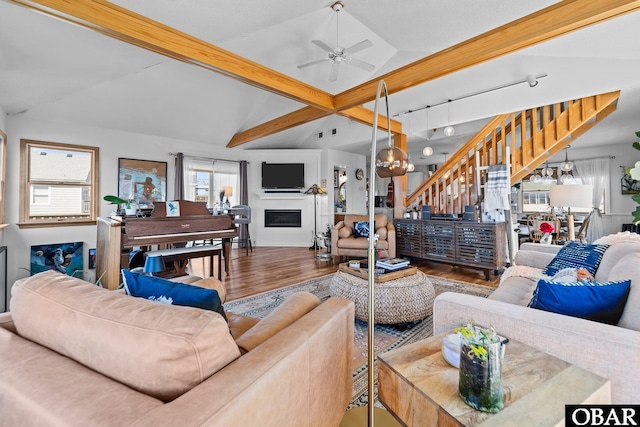 living room featuring lofted ceiling with beams, a fireplace, stairs, a ceiling fan, and wood finished floors