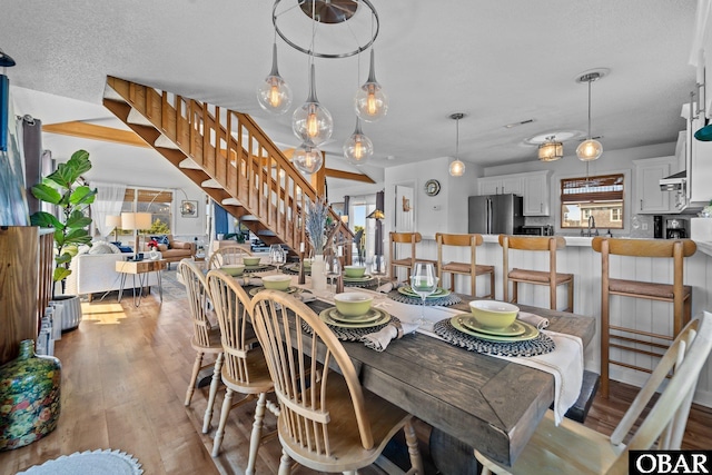 dining area featuring light wood-style floors, visible vents, and stairway