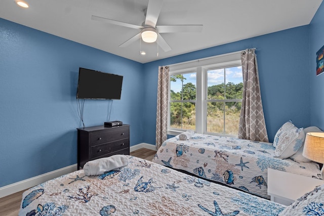 bedroom with ceiling fan, baseboards, and wood finished floors