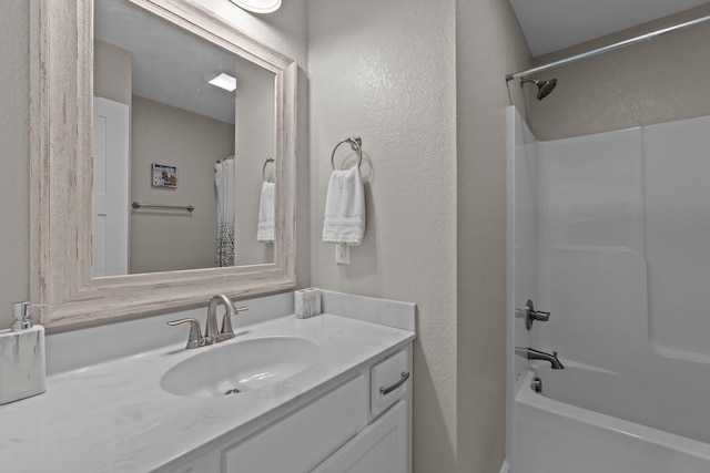 full bathroom with a textured wall, shower / tub combo, and vanity