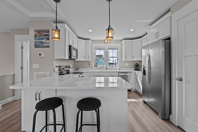 kitchen with stainless steel appliances, hanging light fixtures, and white cabinets