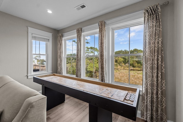 recreation room featuring baseboards, visible vents, and wood finished floors