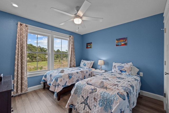 bedroom featuring a ceiling fan, baseboards, and wood finished floors