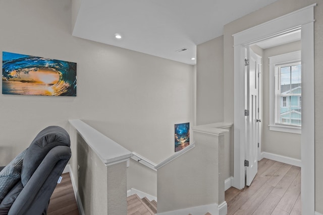 hall with light wood-style floors, recessed lighting, baseboards, and an upstairs landing