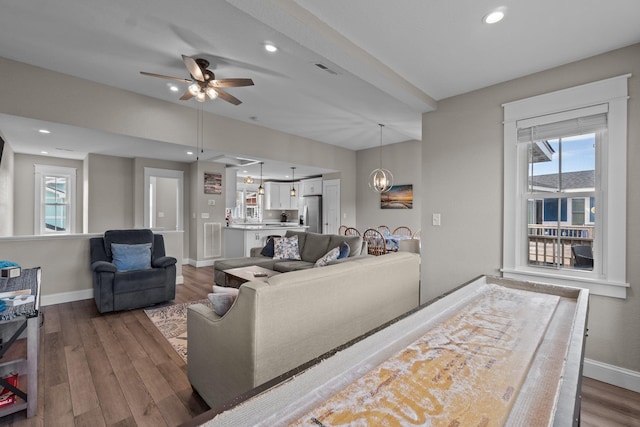 living room with a wealth of natural light, visible vents, baseboards, and wood finished floors