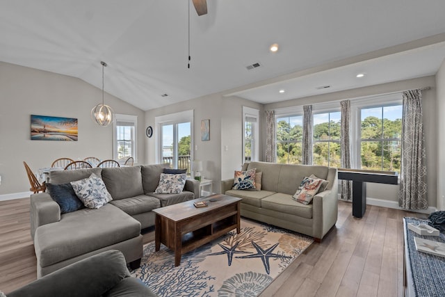 living area featuring visible vents, an inviting chandelier, vaulted ceiling, wood finished floors, and baseboards