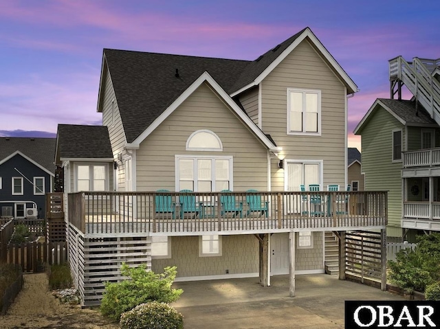 back of property with a deck and a shingled roof