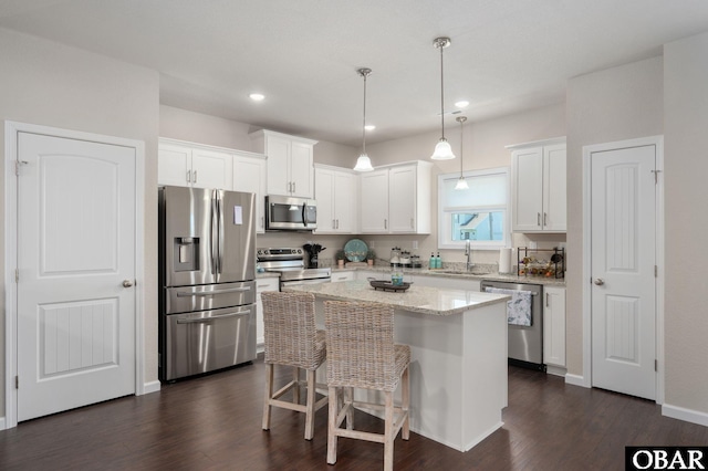 1804 Harbour View Dr Lot 91-O, Kill Devil Hills, NC 27948 - kitchen featuring appliances with stainless steel finishes, white cabinetry, a center island, dark wood-style flooring, and a kitchen breakfast bar