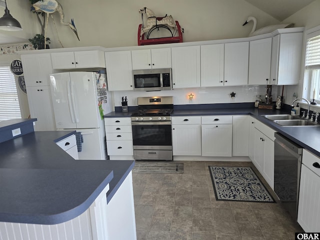 27057 Ocean Street Unit, Salvo, NC 27972 - kitchen with appliances with stainless steel finishes, a sink, dark countertops, white cabinetry, and vaulted ceiling