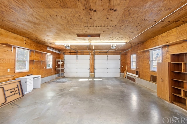 garage with a garage door opener, wooden ceiling, and wooden walls